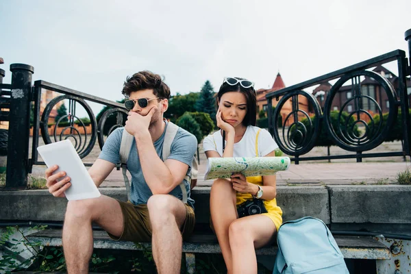 Sad and handsome man looking at digital tablet and asian woman looking at map — Stock Photo