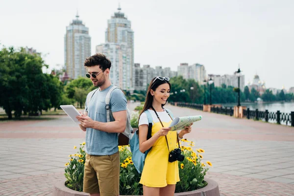Красивий чоловік тримає цифровий планшет і азіатська жінка тримає карту — стокове фото