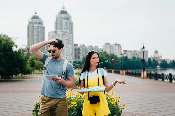 Schöner Mann mit digitalem Tablet und asiatische Frau mit Karte — Stockfoto