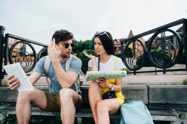 Triste uomo holding digitale tablet e asiatico donna holding mappa — Foto stock