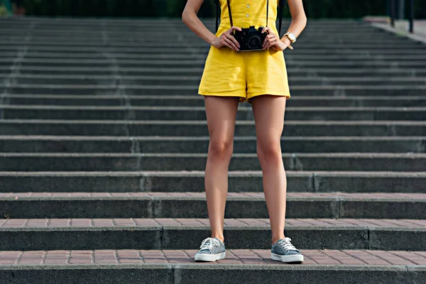 Cropped view of woman in overalls holding digital camera — Stock Photo