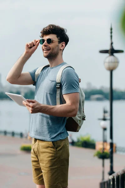 Красивий чоловік в окулярах посміхається і тримає цифровий планшет — стокове фото