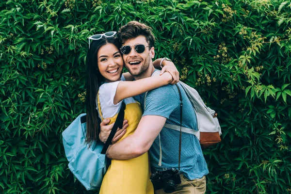 Handsome man and asian woman hugging and looking at camera — Stock Photo