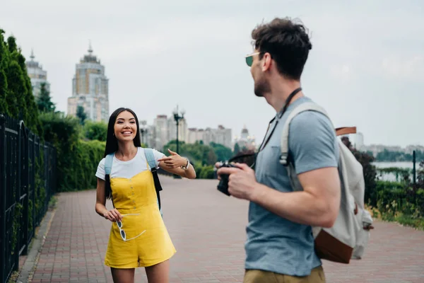 Uomo con fotocamera digitale e asiatica donna parlando e guardando l'un l'altro — Foto stock