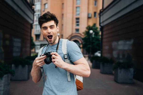 Schöner Mann im T-Shirt mit Digitalkamera und Blick in die Kamera — Stockfoto