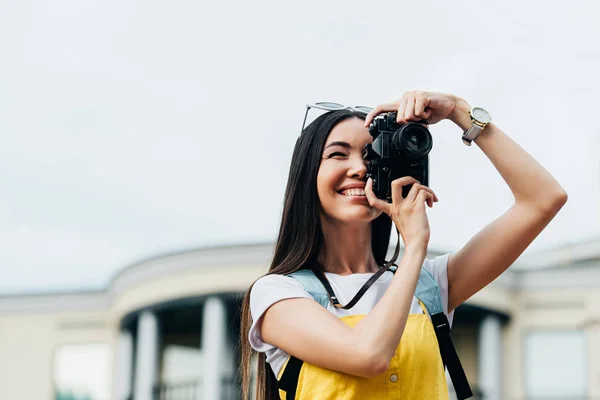 Attrayant et asiatique femme avec des lunettes souriant et prendre des photos — Photo de stock