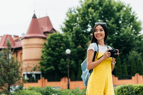 Attrayant et asiatique femme avec appareil photo numérique regardant loin — Photo de stock