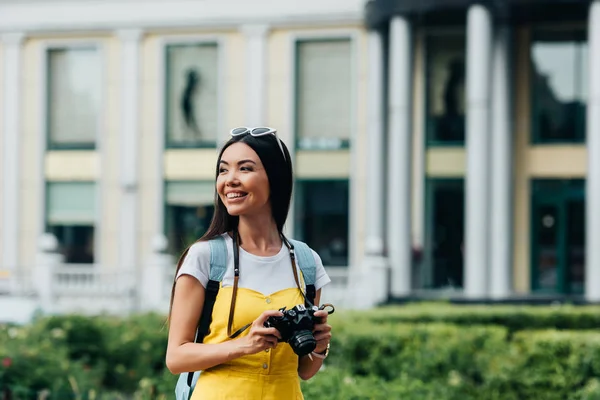 Привлекательная и азиатская женщина с цифровой камерой, отворачивающаяся — стоковое фото