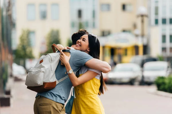 Man and asian woman hugging and holding paper cup — Stock Photo