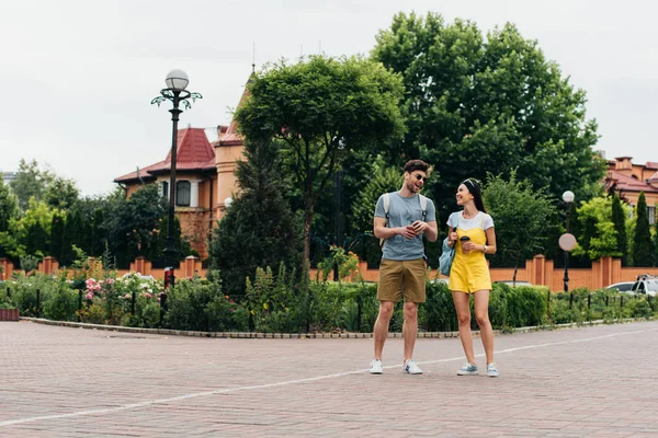 Schöner Mann und asiatische Frau lächeln und halten Pappbecher — Stockfoto