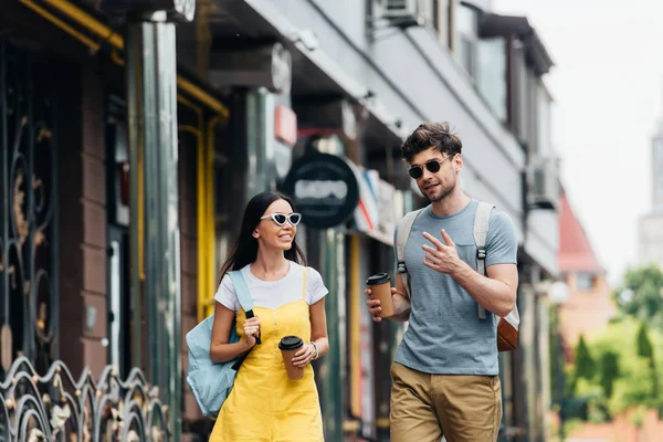 Bel homme et asiatique femme parler et tenant des tasses en papier — Photo de stock