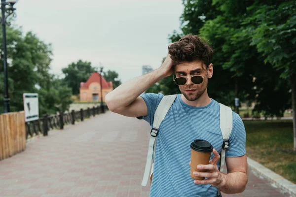 Homem bonito em t-shirt segurando copo de papel e olhando para longe — Fotografia de Stock