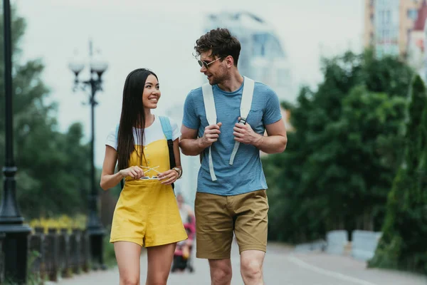 Guapo hombre y asiático mujer con gafas mirando uno al otro - foto de stock