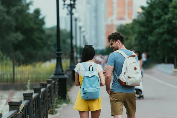 Visão traseira de homem e mulher com mochilas falando fora — Fotografia de Stock