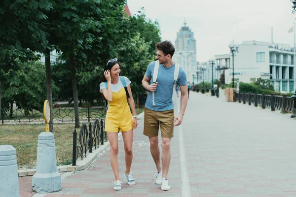 Guapo hombre y asiático mujer caminando y mirando el uno al otro - foto de stock