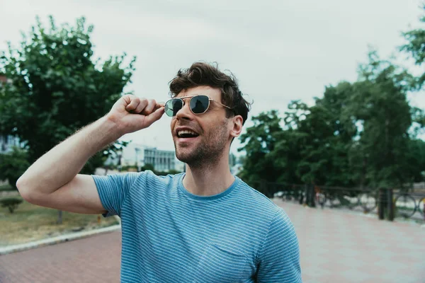 Uomo sorridente e bello in t-shirt e occhiali guardando altrove — Foto stock