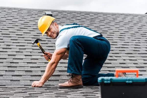 Selective focus of handsome handyman repairing roof — Stock Photo