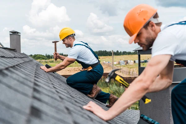 Foco seletivo de handyman bonito reparar telhado com colega — Fotografia de Stock