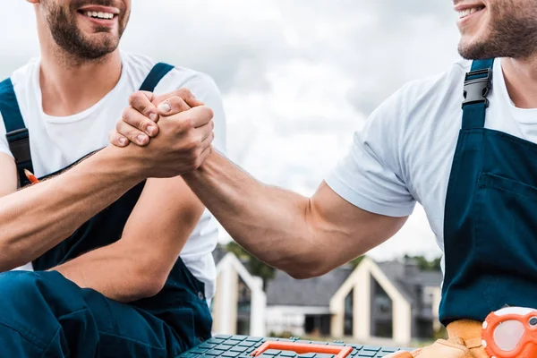 Cropped view of handymen holding hands against sky with clouds — Stock Photo