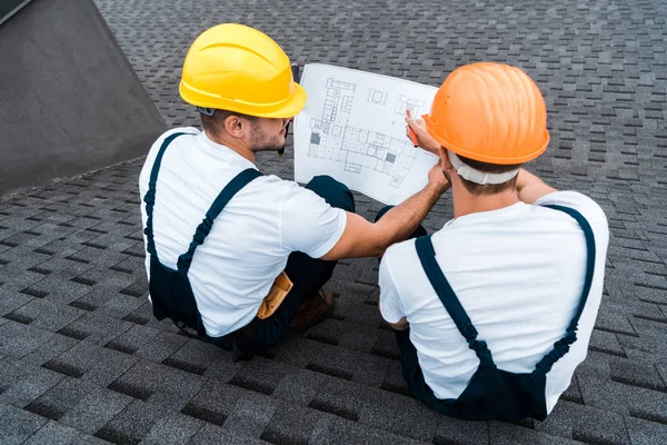Overhead view of builders in helmets looking at blueprint — Stock Photo