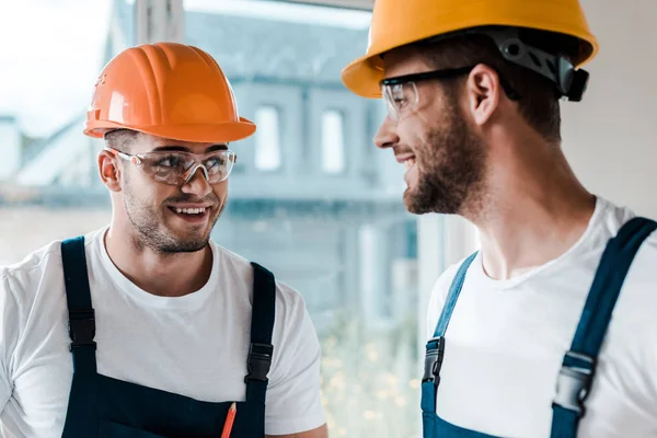 Heureux réparateurs dans les casques et les lunettes en se regardant — Photo de stock