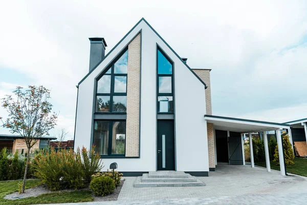 Neues Luxus-Haus in der Nähe von grünen Bäumen und Sträuchern auf Gras — Stockfoto