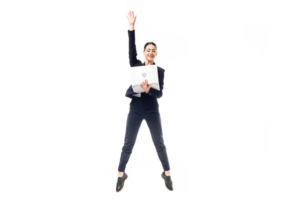Attraente donna d'affari che salta mentre tiene il computer portatile isolato su bianco — Foto stock