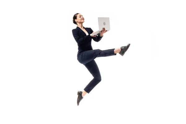 Atractiva y sonriente mujer de negocios bailando mientras usa un teléfono inteligente aislado en blanco - foto de stock