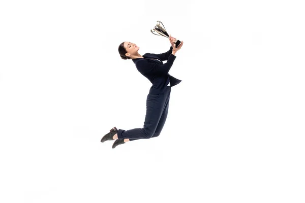 Beautiful businesswoman jumping in dance while holding trophy cup isolated on white — Stock Photo