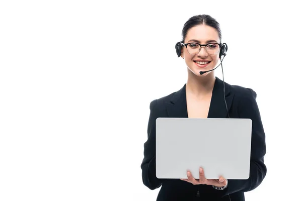 Sonriente operador del centro de llamadas en auriculares usando el ordenador portátil mientras mira la cámara aislada en blanco - foto de stock