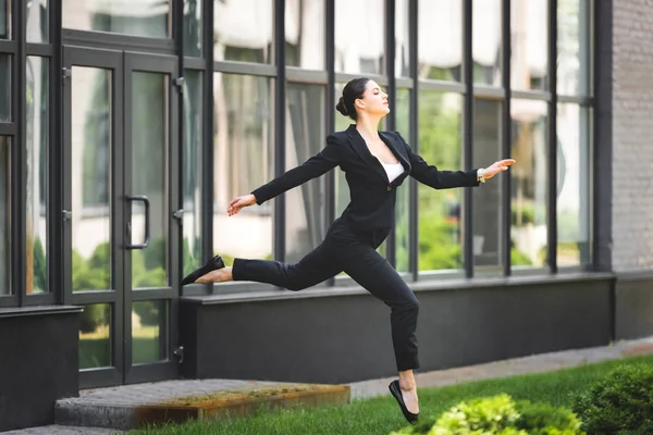 Hermosa, elegante mujer de negocios levitando cerca del edificio de oficinas - foto de stock