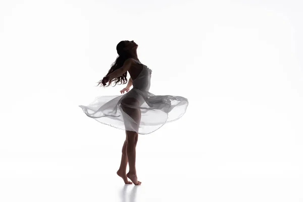 Hermosa bailarina elegante en vestido blanco bailando sobre fondo blanco - foto de stock