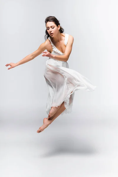 Atraente, gracefull bailarina em vestido branco dançando em fundo cinza — Fotografia de Stock