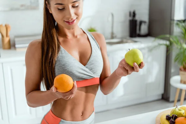 Щаслива дівчина в спортивному одязі, що тримає смачні фрукти — стокове фото