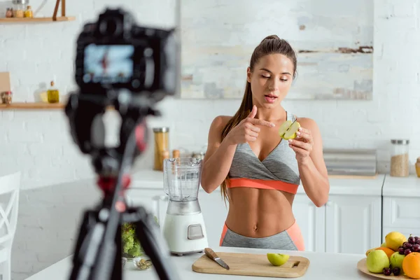 Atractiva mujer señalando con el dedo a la mitad de la manzana - foto de stock