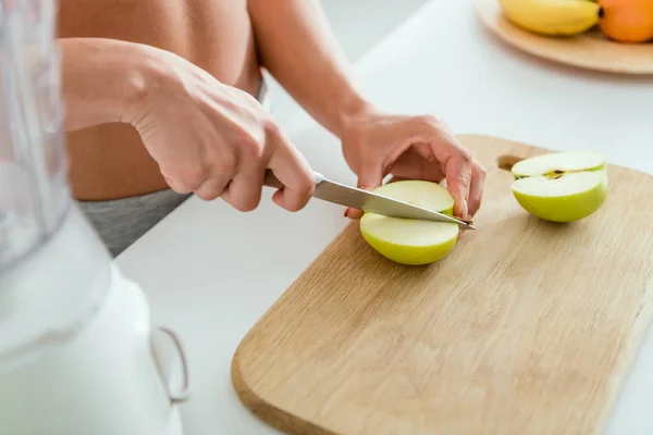 Обрезанный вид девушки резки вкусное яблоко на доске — стоковое фото