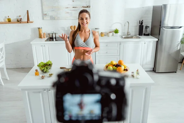 Selektiver Fokus glücklicher Mädchen, die in der Nähe von Früchten und Digitalkamera gestikulieren — Stockfoto