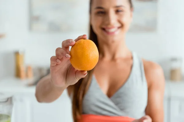 Messa a fuoco selettiva di felice giovane donna che tiene gustoso arancione — Foto stock