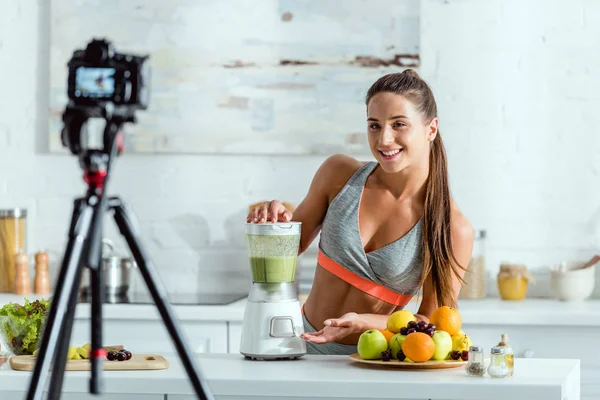 Selective focus of cheerful sportswoman preparing smoothie in blender — Stock Photo