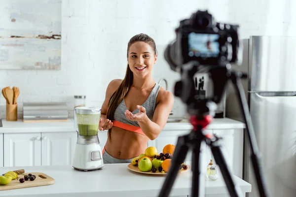 Selective focus of cheerful woman gesturing near blender with smoothie — Stock Photo