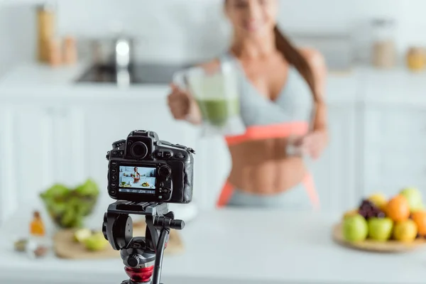 Selektiver Fokus der Digitalkamera mit glücklichem Mädchen, das Smoothie im Glas auf dem Bildschirm hält — Stockfoto