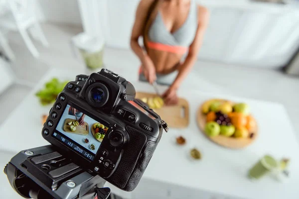 Selektive Fokussierung der Digitalkamera mit Mädchen, das Apfel auf dem Bildschirm schneidet — Stockfoto