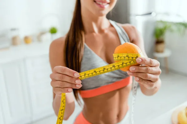 Cropped view of cheerful young woman measuring orange — Stock Photo