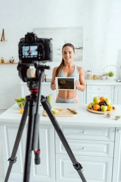 Selective focus of happy video blogger holding digital tablet with blank screen — Stock Photo