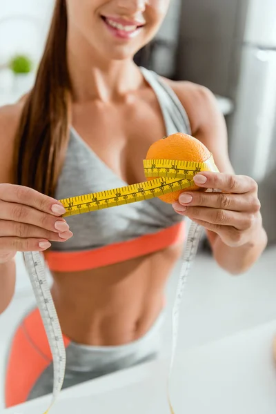 Cropped view of cheerful girl measuring orange — Stock Photo