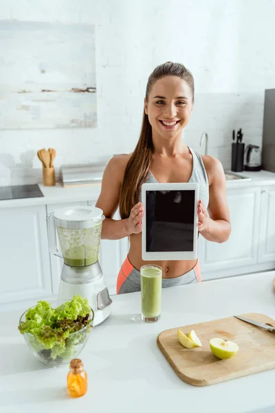 Glückliche junge Frau hält digitales Tablet mit leerem Bildschirm — Stockfoto