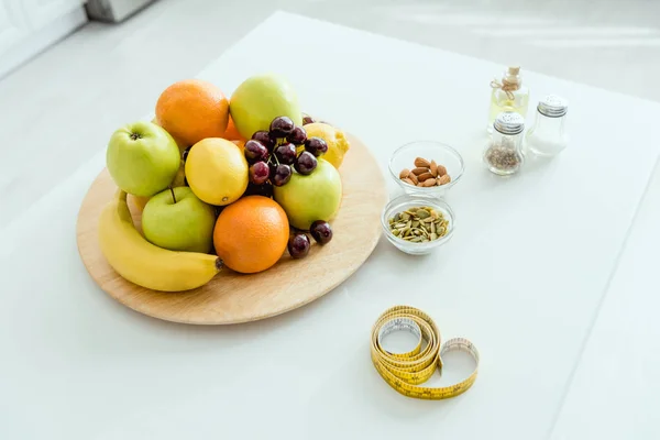 Enfoque selectivo de frutas sabrosas y maduras en la placa cerca de cinta métrica en la mesa - foto de stock