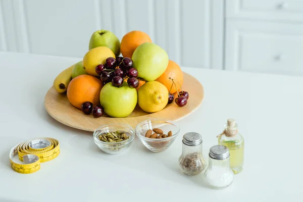 Вкусные и спелые фрукты на тарелке рядом с измерительной лентой на столе — стоковое фото