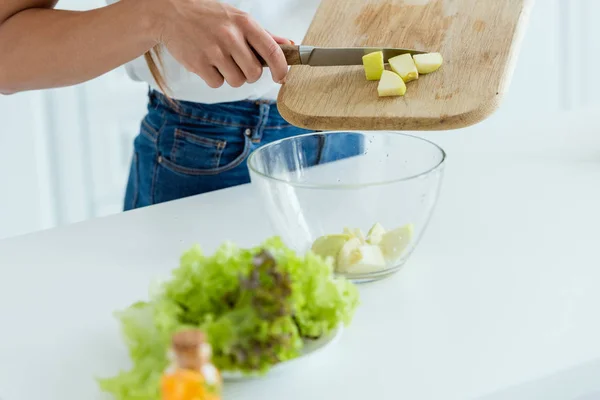 Vista recortada de la mujer poniendo manzana en rodajas en un tazón - foto de stock