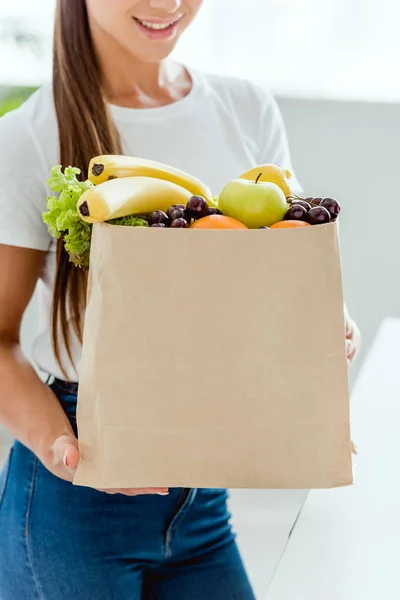 Vista cortada de mulher feliz segurando saco de papel com frutas orgânicas — Fotografia de Stock